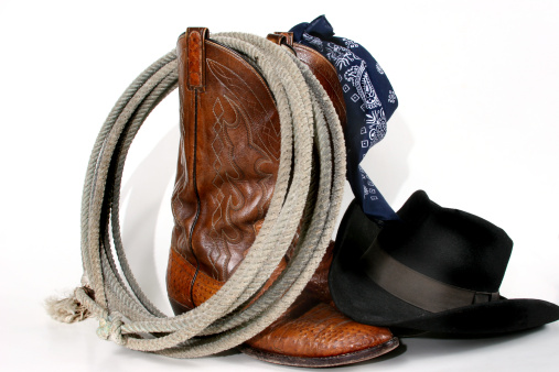 Display of cowboy boots, bandana, hat and rope.  Isolated on white background.  