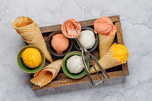 Assorted ice cream flavours in delightful waffle cones, a treat for every taste bud. Over stone background. Flat lay