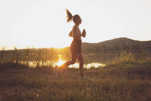 Running. woman plays sports at sunset on the ocean. preparation for the marathon. life photo. fitness and yoga in the park, silhouette.