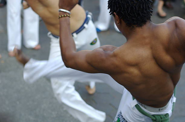 Brazilian Capoeira Fighters in Combat Muscular back of a man performing high kicks in capoeira (Brazilian martial arts) combat deltoid photos stock pictures, royalty-free photos & images