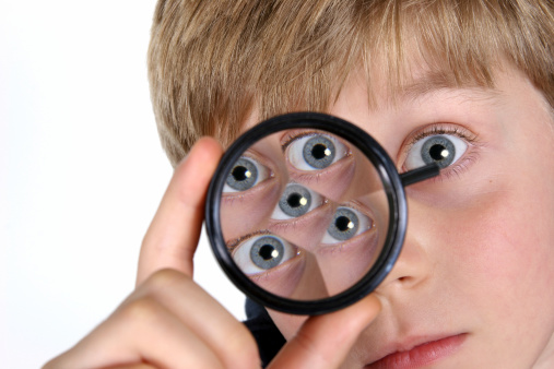 Young boy looking through a prism.  Education, school, classroom learning. Elementary student. 
