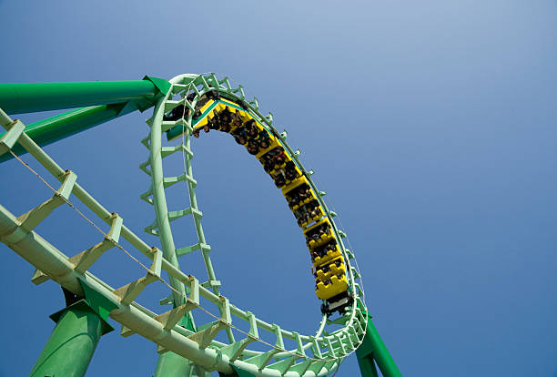 Spiral loop of a green steel roller coaster Roller coaster looping the loop at amusement park, space for text. rollercoaster photos stock pictures, royalty-free photos & images
