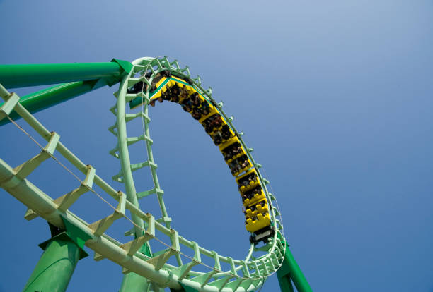 Spiral loop of a green steel roller coaster Roller coaster looping the loop at amusement park, space for text. rollercoaster stock pictures, royalty-free photos & images