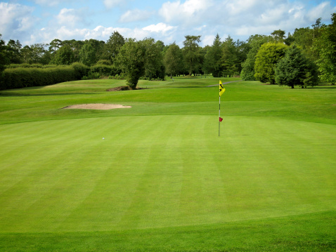 Putting green on a golf course on a sunny day with view of the fairway