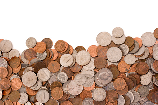 USA coins, American small change currency piled against a white background, forming a texture pattern bottom border frame for page layout. A large group of pennies, nickels, dimes, and quarters are randomly stacked and heaped together to represent building wealth, making money, savings, finances, abundance of cash, and found treasure.