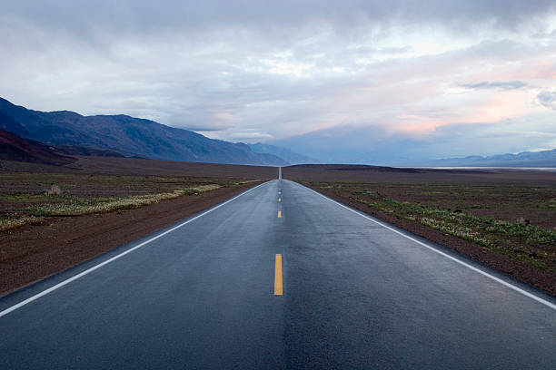 Highway to Infinity: seemingly endless road under a dramatic sky stock photo