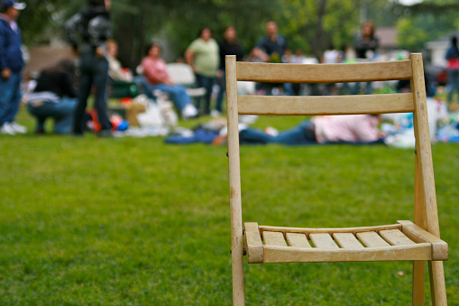 Empty chair maybe where Grandma sits is empty at family outdoor celebration in a park with Hispanic relatives