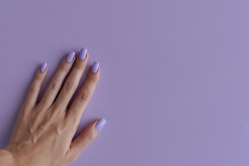 Mano de hembra con uñas de color púrpura. Manicura gelish. Uñas cuadradas con esmalte de uñas permanente de color lavanda de moda photo