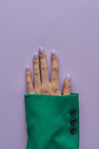 Mano femenina con manicura gelish de moda con uñas de color púrpura. Colores verde y púrpura photo