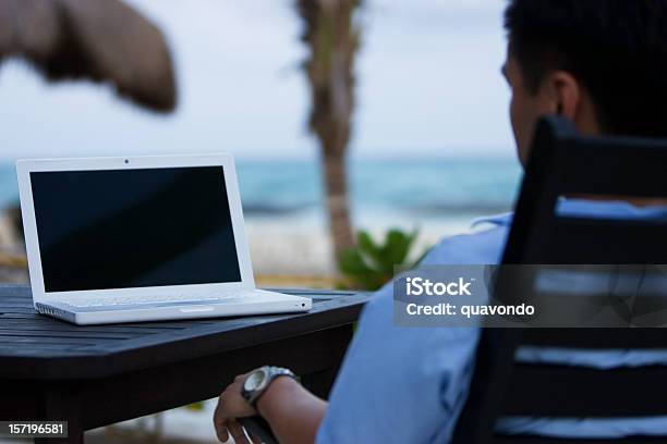 Hombre Asiático Utilizando El Ordenador Portátil Con Pantalla En Blanco En La Playa Foto de stock y más banco de imágenes de Playa