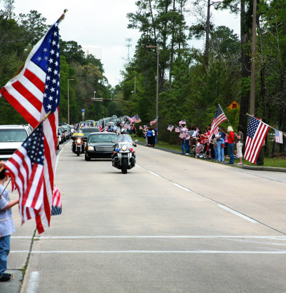 Motorcade on main street USA.  American flags waving.