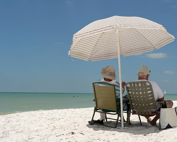 Group mature women wearing beach hats and smiling while standing on a tropical beach. Older ladies have fun in outdoor leisure activity in holiday vacation summer lifestyle. Elderly friends lifestyle