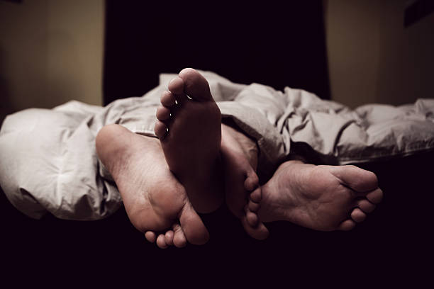 Couples Feet Out of Sheets stock photo