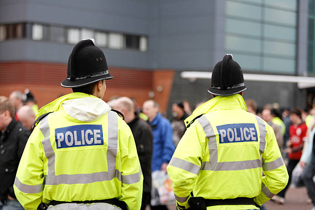 dois elementos da polícia britânica tradicional capacetes de controle de multidão. mais abaixo. - grande manchester - fotografias e filmes do acervo