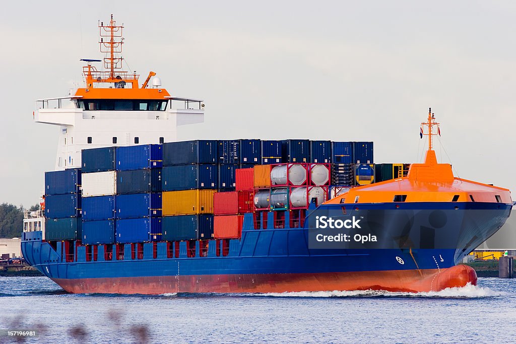 Orange and blue container ship Orange and blue containership sailing up the river with cargo containers Barge Stock Photo