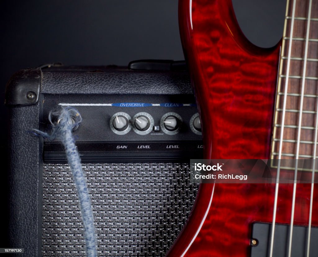 Bass Guitar and Amplifier An electric bass guitar leaning against a guitar amplifier. Focus is on the knobs of the amp.  Black background. Amplifier Stock Photo