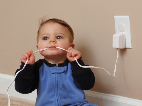 A 6-month old baby boy chews on an electrical cord. Don’t worry the power was off during the shoot.
