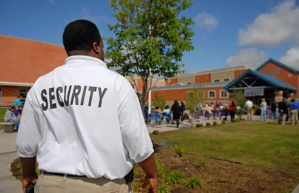 Security guard at a public junior high school -- students OOF in background