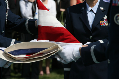 Military personel folding the American Flag at a funeral.