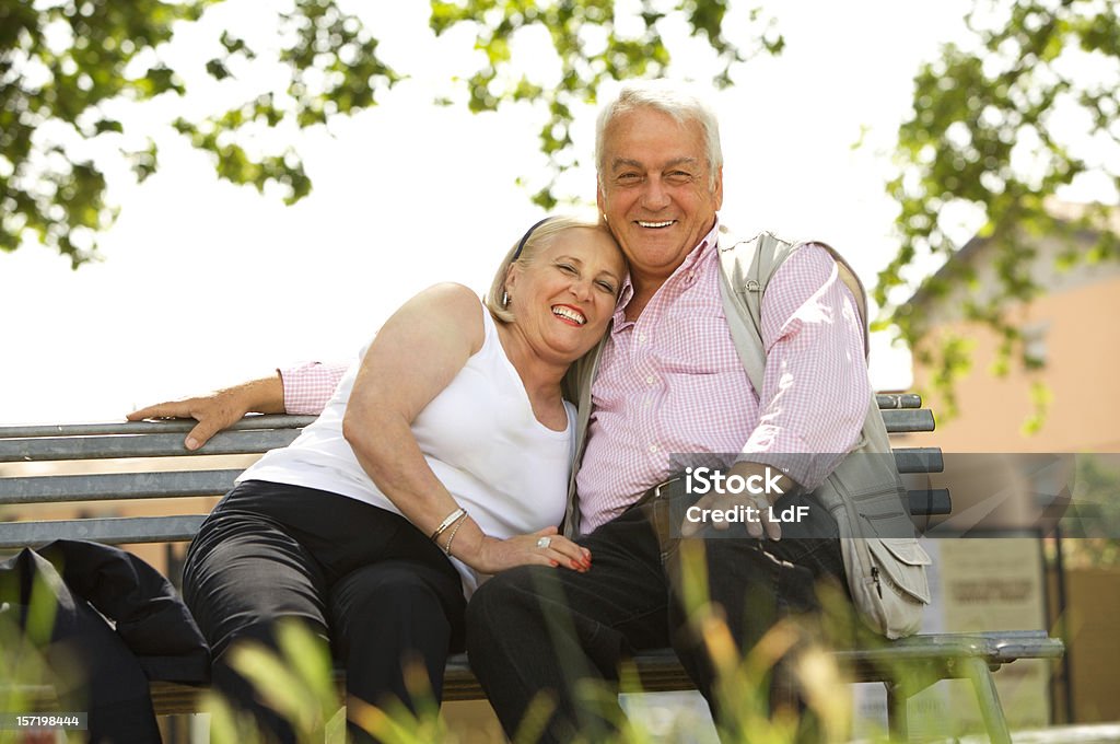 Feliz sênior casal sentado em um banco no parque - Foto de stock de 60-64 anos royalty-free