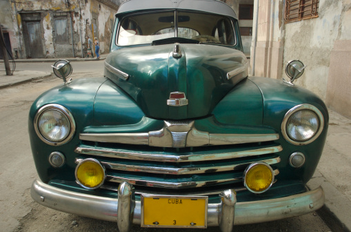 Classic American car in shiny green stands parked on a Havana street