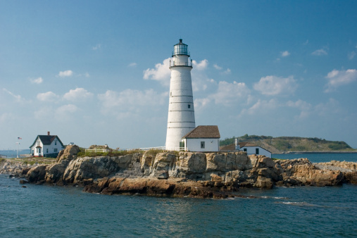 A picturesque lighthouse stands atop a rocky cliff, overlooking the beautiful blue waters of the ocean