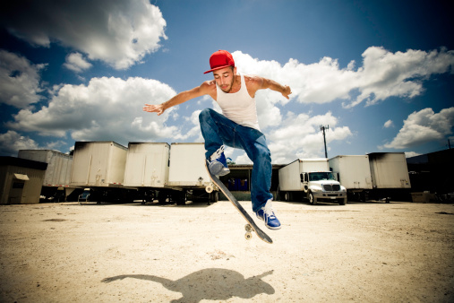 Young man jumping into the air with  skateboard, action shot, intended vignetting, below you see a 'kangaroo' shaped REAL shadow of the skateboarder, no editing,just luck.