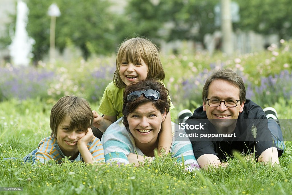 Feliz familia de cuatro yacer en la hierba la primavera - Foto de stock de 30-39 años libre de derechos