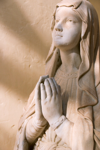 Statue of the Madonna bathed in a soft light with shadows falling across.