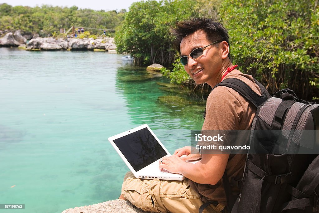 Uomo asiatico utilizzando il computer portatile su escursione - Foto stock royalty-free di Ambientazione esterna