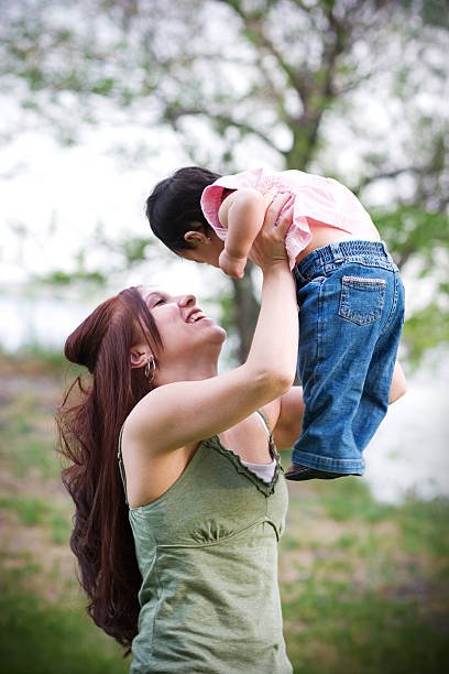 szczęśliwa młoda matka z dzieckiem na zewnątrz w charakterze podnoszenia - teenage pregnancy mother social issues family zdjęcia i obrazy z banku zdjęć