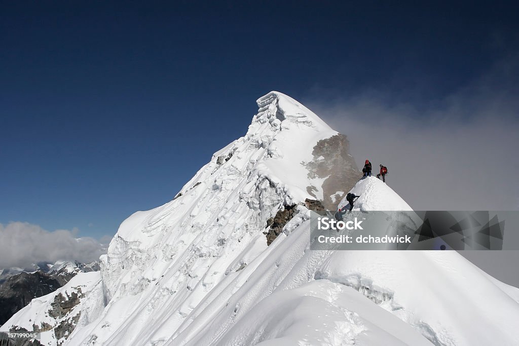 Two climbers almost at the top of a snowy mountain top Climbers moving onto a subsidiary peak of a very large mountain. This is Lobuche East, the most difficult of the "trekking peaks" in the Khumbu region of the Himalaya. Please take a look at some other photos from the same region.  Mountain Peak Stock Photo