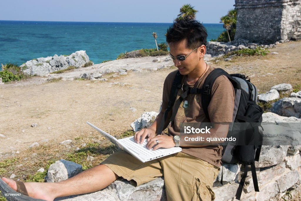 Hombre joven asiático utilizando el ordenador portátil excursionismo en México, espacio de copia - Foto de stock de Ordenador portátil libre de derechos