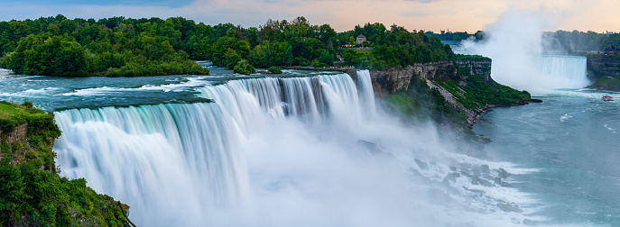 A panoramic long exposure photo of the American - Canadian waterfalls Niagara Falls in dusk.