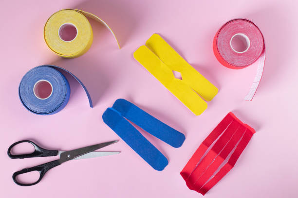 istock Colorful kinesiology tape, scissors and different shape cuts for applique on pink background 1572027161