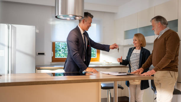 istock Estate agent giving key to costumer 1572059012