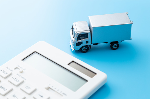 Truck and calculator on blue background.
