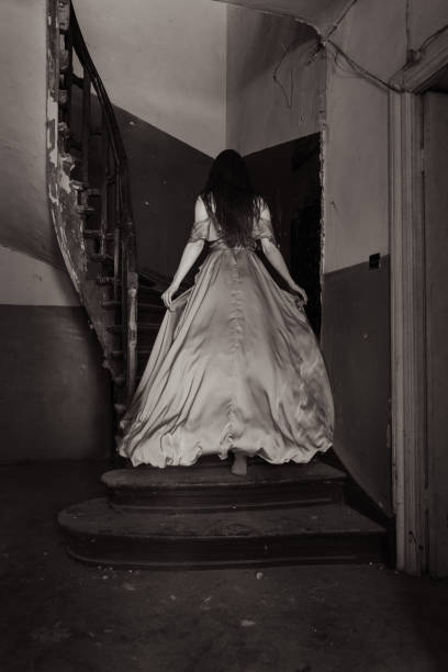 Scary scene with a young woman acting like a ghost in an abandoned house.