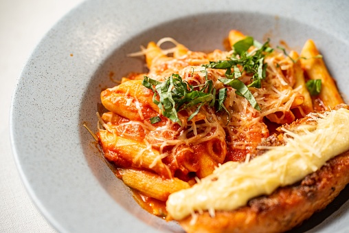 A tantalizing plate of freshly-cooked Italian pasta, covered with a generous sprinkling of herbs and melted cheese