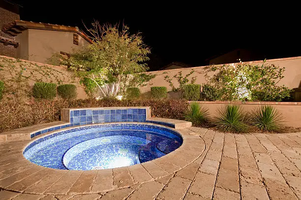 Wide angle shot of a private backyard spa at night.