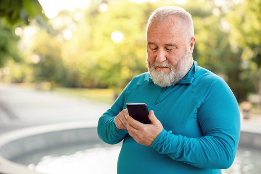 Overweight man using mobile phone in public park