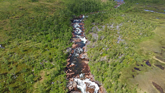 Drone photo of rushing river with red stones in the lonely landscape of Norway