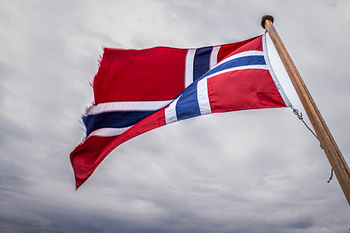 The Norwegian flag flying from the flag pole of a schooner sail boat moored in Oslo harbour.