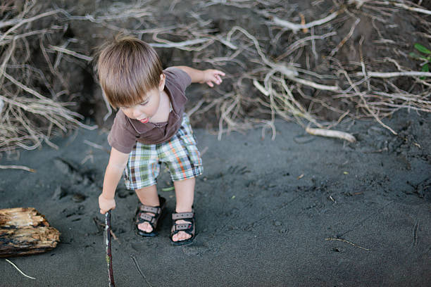 Boy drawing in sand. stock photo