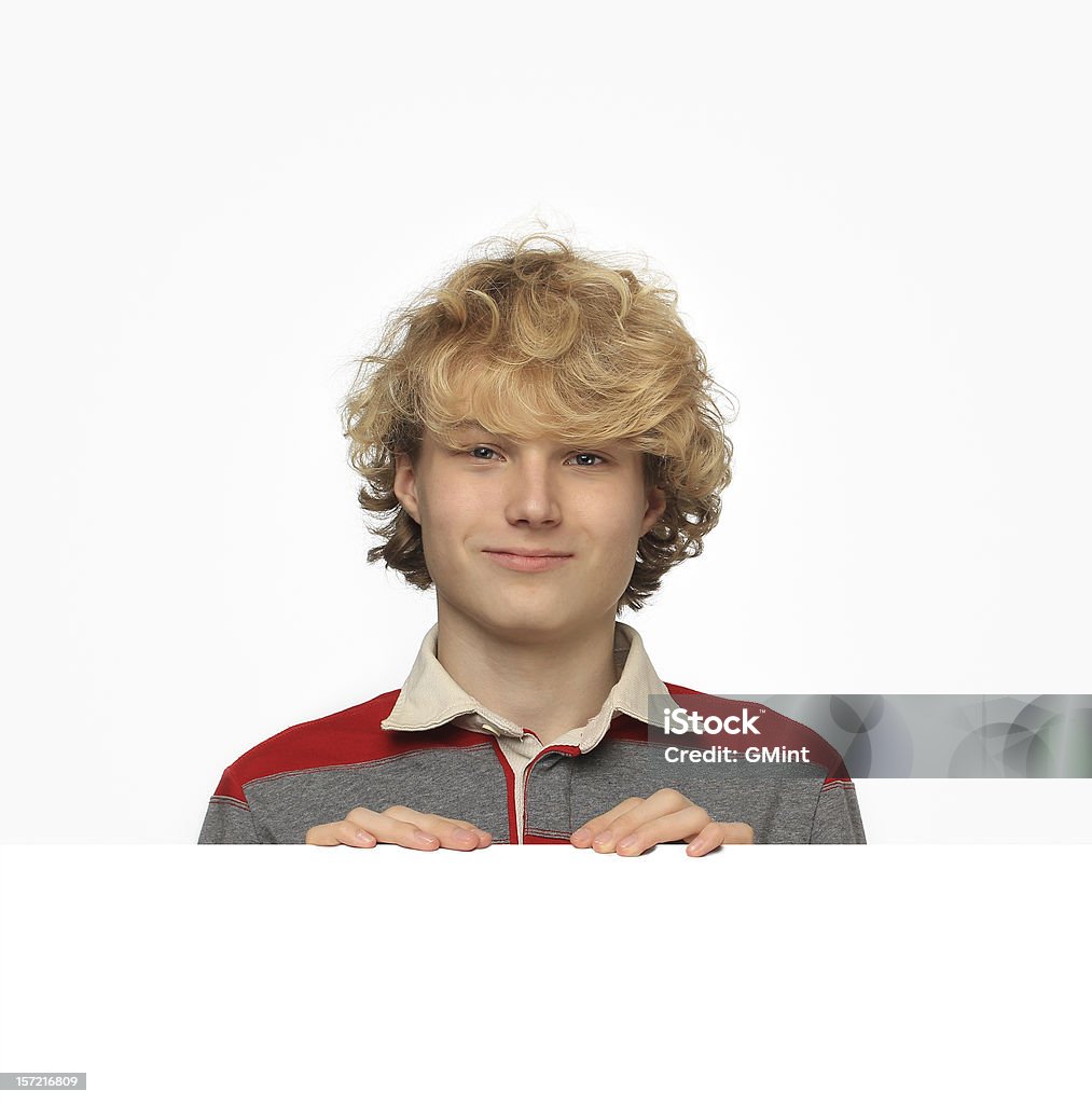 Smiling teenage boy above white blank billboard on neutral background Adolescence Stock Photo