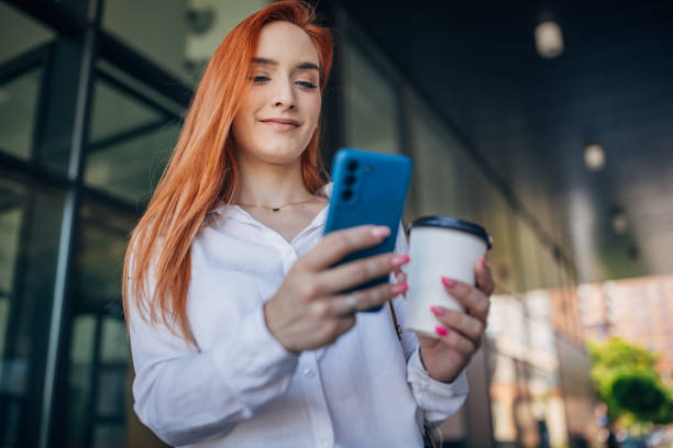 istock Woman with mobile next to buildings 1572170685