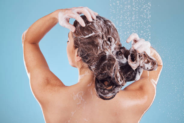Kobieta, plecy i szampon, pielęgnacja włosów pod prysznicem i higiena z kroplami wody na niebieskim tle. Pielęgnacja, pielęgnacja kosmetyczna i zrównoważony rozwój, kobieta i poranna rutyna, mydło lub pianka we włosach – zdjęcie