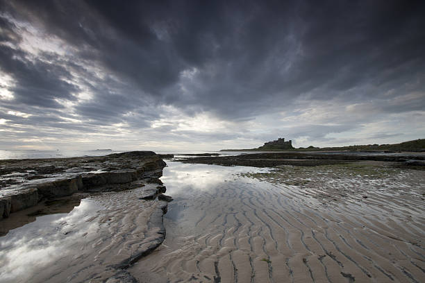 castillo de bamburgh al amanecer - bamburgh northumberland england beach cloud fotografías e imágenes de stock