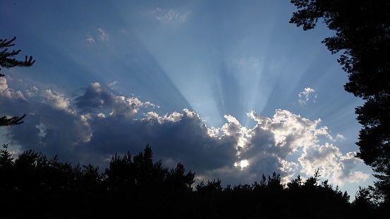 suns rays from behind clouds blue sky