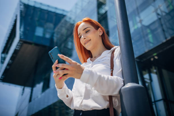 istock Woman with mobile next to buildings 1572261420
